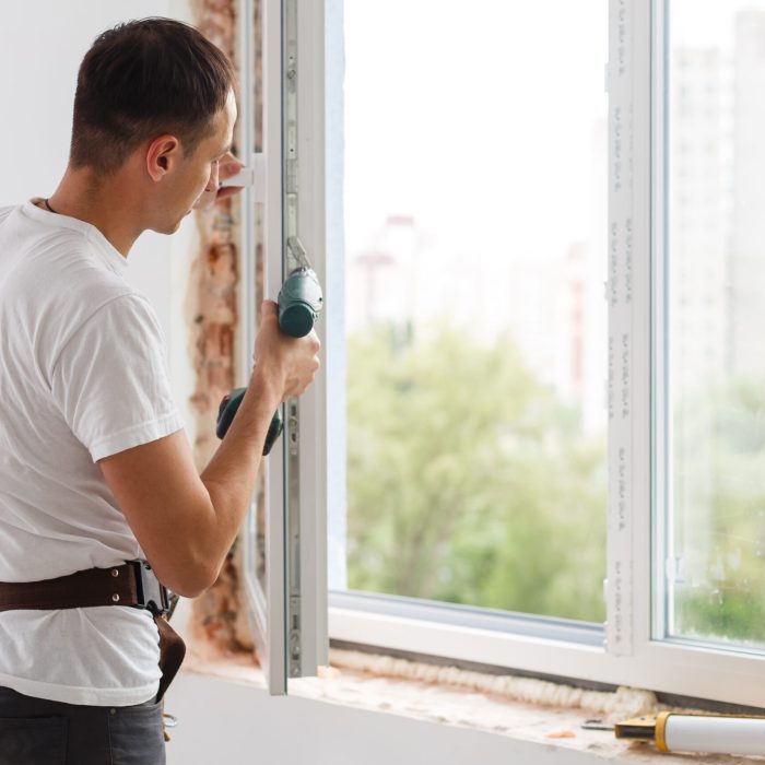 Young handyman repair window with screwdriver